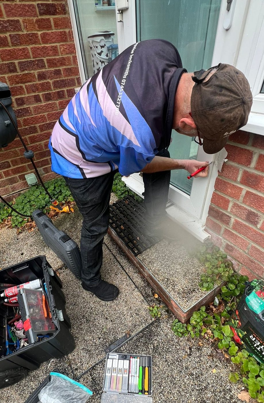 Bugsy marking up a uPVC conservatory door frame, tool cases open on the path