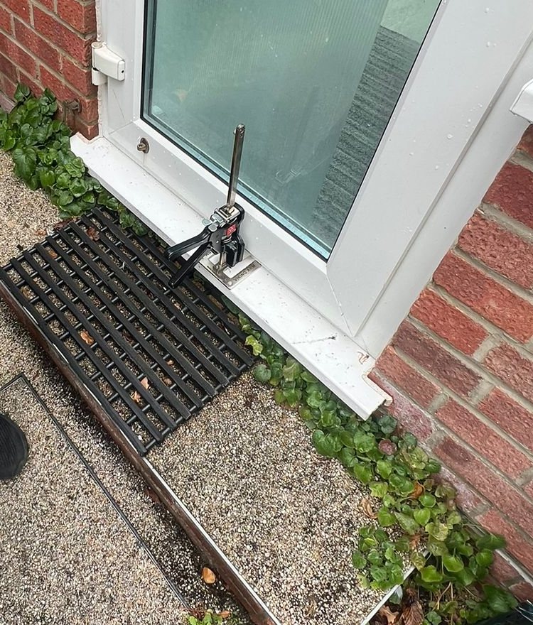 A Viking Arm lifting jack at the threshold, holding the door at height while the hinges are set