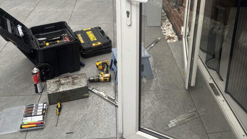 uPVC French doors standing open on a patio in St Denys, with locksmith tools laid out beside them