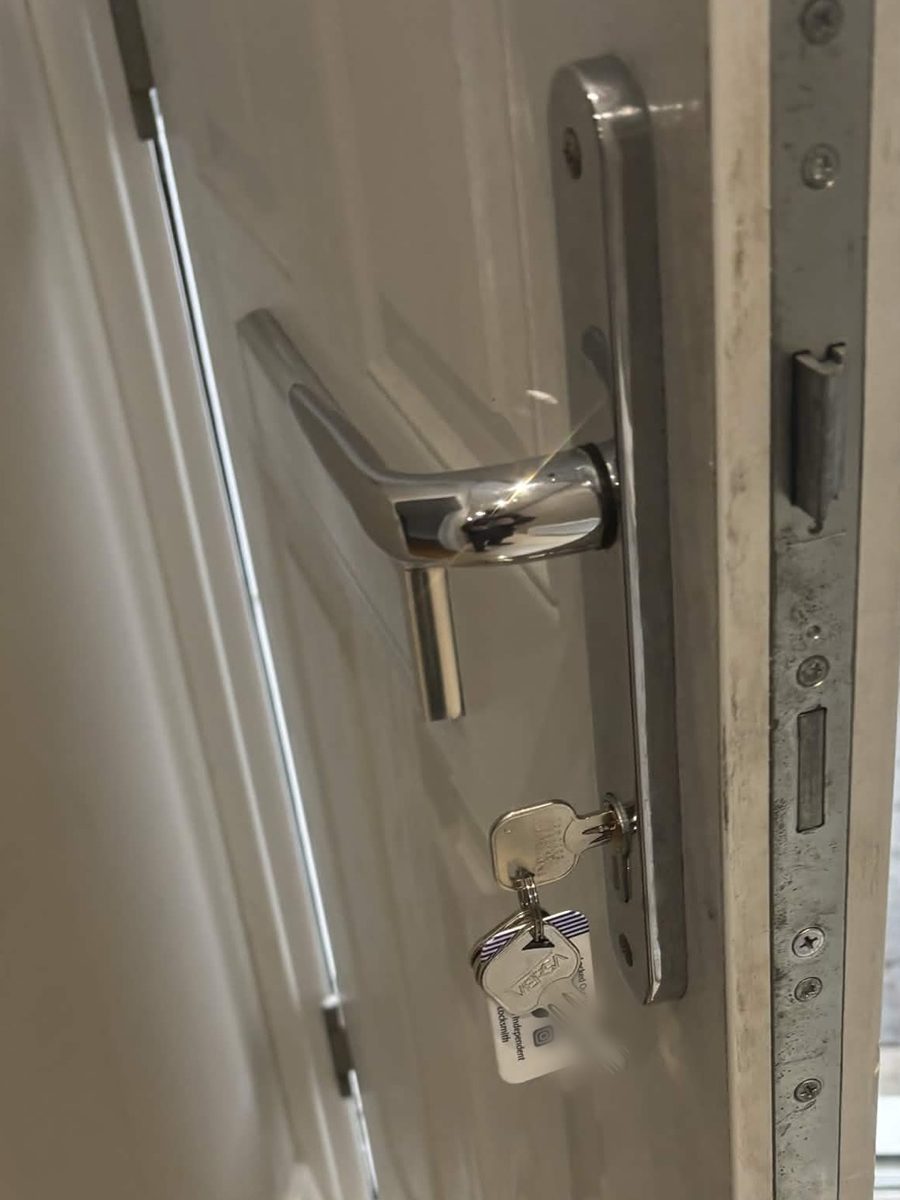 Front door edge showing the multipoint lock, with a new cylinder and keys on a KeyWise key tag