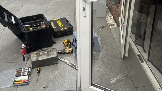 uPVC French doors standing open on a patio in St Denys, with locksmith tools laid out beside them
